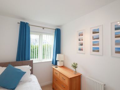 A bedroom with a bed, dresser, and window at Blissful Ocean Breeze Perranporth