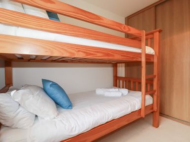 A bunk bed with white bedding and pillows at Blissful Ocean Breeze in Perranporth