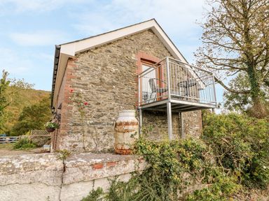 Stone house with a small metal balcony and vintage milk churn outside at Field View in Llanybydder