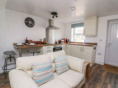 A kitchen and living area with a white sofa and striped cushions at Field View in Llanybydder