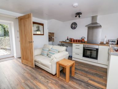 A small kitchen with a sofa a wooden table and glass door at Field View in Llanybydder