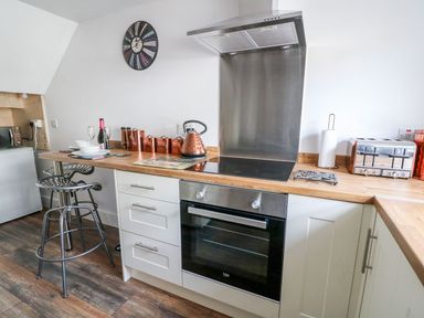 A kitchen with a wooden countertop stove oven copper canisters and stools at Field View in Llanybydder