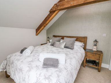 A bedroom with a double bed towels on the bed and a wooden bedside table at Field View in Llanybydder