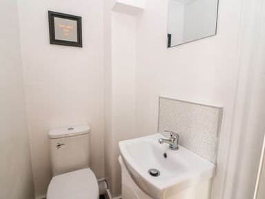 A small bathroom with a toilet sink mirror and a framed sign on the wall at Field View in Llanybydder