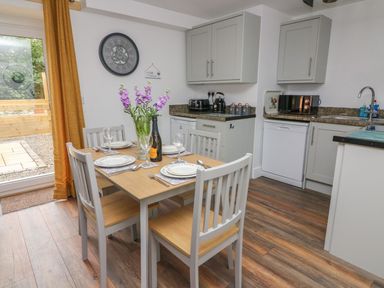 A kitchen with a dining table set for four and kitchen cabinets at Garden View in Llanybydder