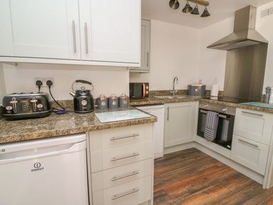 A kitchen with white cabinets a toaster kettle and storage canisters on the countertop at Garden View in Llanybydder