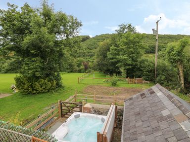 A backyard with a hot tub a fenced garden and trees at Garden View in Llanybydder
