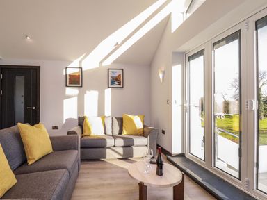 A living room with sofas and cushions near glass doors at Lake View in Kestle Mill near Quintrell Downs