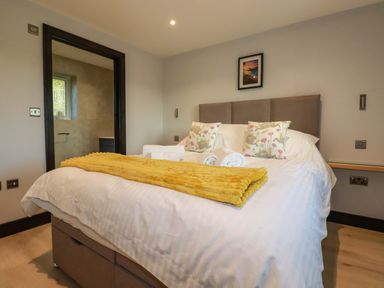 A bedroom with a bed with white linens and a yellow throw at Lake View Kestle Mill near Quintrell Downs