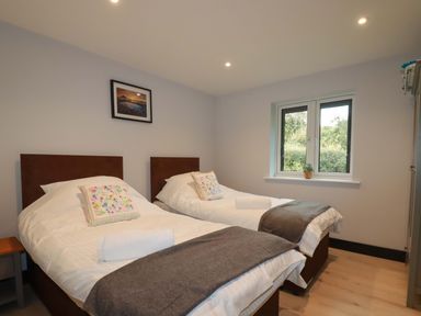 A bedroom with two single beds a window and a framed picture at Lake View in Kestle Mill near Quintrell Downs