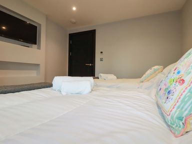 A bedroom with two beds white towels and a wall mounted television at Lake View in Kestle Mill near Quintrell Downs