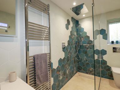 A bathroom with hexagonal wall tiles a walk in shower and a towel rack at Lake View in Kestle Mill near Quintrell Downs