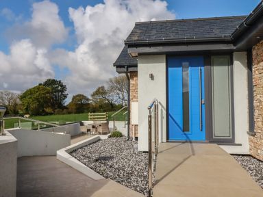 An entrance with a blue door and patio furniture at Lake View in Kestle Mill near Quintrell Downs