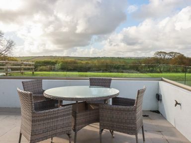 An outdoor seating area with a table and chairs at Lake View in Kestle Mill near Quintrell Downs