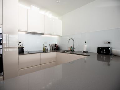 A modern kitchen with white cabinets a corner countertop a sink toaster and coffee maker at Apartment 17 Abbey Sands in Torquay