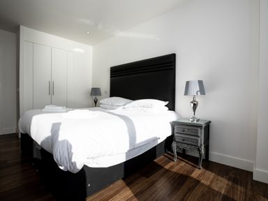 A bedroom with a double bed white wardrobe bedside tables and lamps at Apartment 17 Abbey Sands in Torquay
