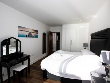 A bedroom with a bed bedside tables with lamps a dressing table and a wall wardrobe at Apartment 17 Abbey Sands in Torquay