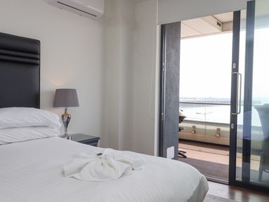 A bedroom with a bed lamp and sliding glass doors leading to a balcony at Apartment 17 Abbey Sands in Torquay