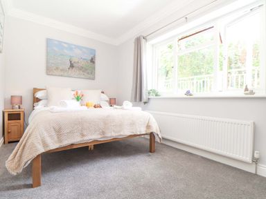 A bedroom with a bed and bedside tables under a window at Lake View Swanpool Nr Falmouth