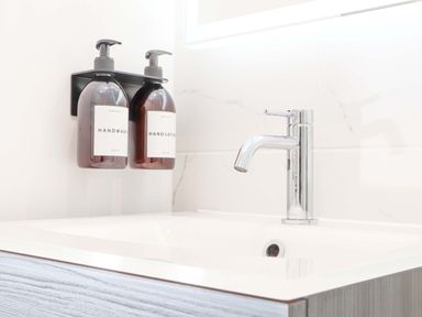 A bathroom sink with a chrome faucet and two wall-mounted bottles labeled handwash and hand lotion at Lake View in Swanpool Nr Falmouth