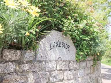 Stone wall with the word Lakeside engraved surrounded by plants and flowers at Lake View Swanpool Nr Falmouth
