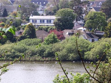 A riverside view of houses and trees with a body of water in the foreground at Lake View in Swanpool Nr Falmouth