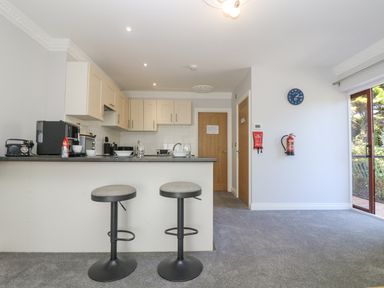 A kitchen with two bar stools a counter appliances and cabinets at Lake View in Swanpool Nr Falmouth