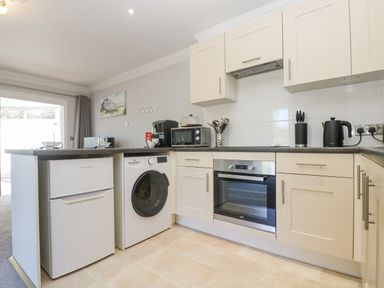 A kitchen with white appliances and cream cabinets at Lake View in Swanpool Nr Falmouth