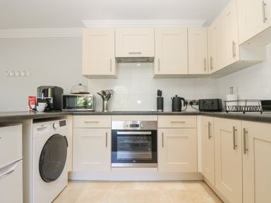 A kitchen with cream cabinets and appliances including an oven washing machine microwave and toaster at Lake View Swanpool Nr Falmouth