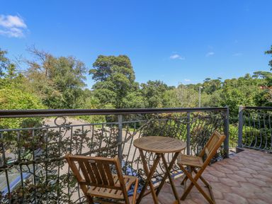A balcony with wooden table and chairs overlooking trees and greenery at Lake View in Swanpool Nr Falmouth