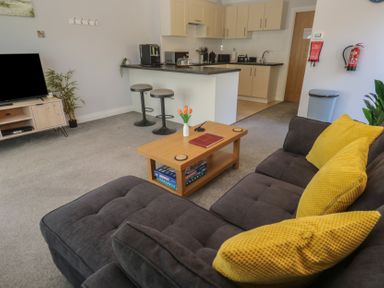 A living room with a sofa and kitchen area at Lake View in Swanpool, Nr Falmouth