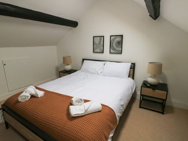 A bedroom with a double bed two bedside tables with lamps and framed pictures on the wall at 1 Mona Terrace in Llanfachraeth