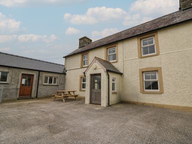 An exterior courtyard area with a picnic table and white textured walls at Castell Y Garn near Newport Beach Pembrokeshire