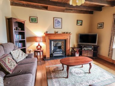 A living room with a sofa a wooden coffee table a fireplace a television and a bookshelf at Castell Y Garn near Newport Beach Pembrokeshire