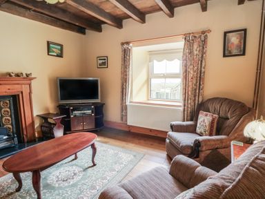 A living room with armchairs a wooden coffee table and a television near a window at Castell Y Garn near Newport Beach Pembrokeshire