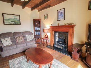 A living room with a sofa a wooden coffee table a fireplace a lamp and a bookshelf at Castell Y Garn near Newport Beach Pembrokeshire