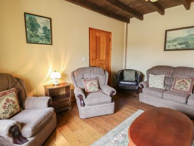A living room with armchairs a sofa a wooden coffee table a side table with lamp and paintings on walls at Castell Y Garn near Newport Beach Pembrokeshire