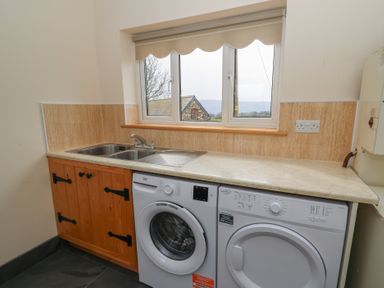 A laundry room with a sink washing machine and dryer under a countertop at Castell Y Garn near Newport Beach Pembrokeshire