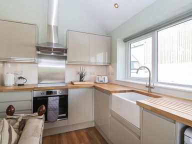 A kitchen with wooden countertops a stainless steel stove and hood a white sink under a window with cabinets Doubletree Cottage Swainsford near Mere