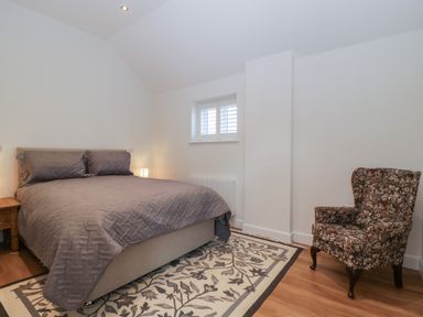 A bedroom with a double bed bedside table lamp patterned armchair and a patterned rug at Doubletree Cottage Swainsford near Mere