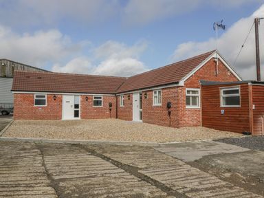 A single story brick building with tiled roof and gravel driveway at Doubletree Cottage in Swainsford near Mere