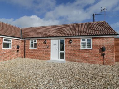 A one-story brick house with a tiled roof and three windows and a white door at Singletree Cottage in Swainsford near Mere
