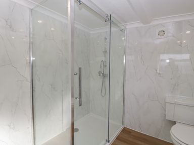 A bathroom with a glass shower enclosure and a toilet at Singletree Cottage in Swainsford near Mere