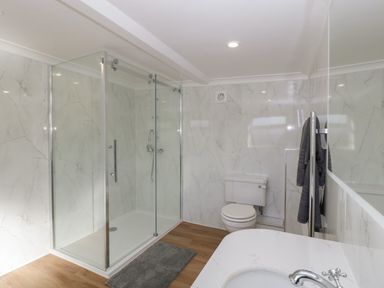 A bathroom with a glass shower enclosure toilet sink and towel rail at Singletree Cottage in Swainsford near Mere