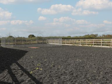 An outdoor fenced area with a dirt ground and a metal enclosure under a cloudy sky at Singletree Cottage in Swainsford near Mere