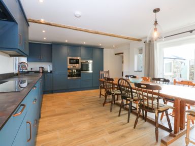 A kitchen featuring cabinets and a dining table at Yr Hen Felin Dyffryn Ardudwy