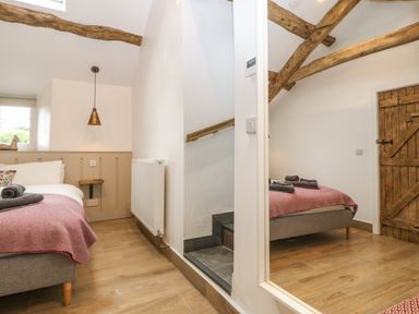 A bedroom with a bed rolled towels wooden ceiling beams and a wooden door at Y Stabl in Dyffryn Ardudwy