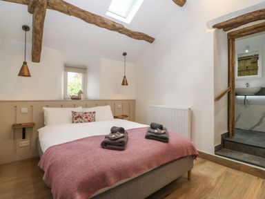 A bedroom with a double bed under wooden beams and a skylight at Y Stabl in Dyffryn Ardudwy