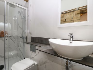 A bathroom with a glass shower enclosure a white toilet and a countertop basin at Y Stabl in Dyffryn Ardudwy