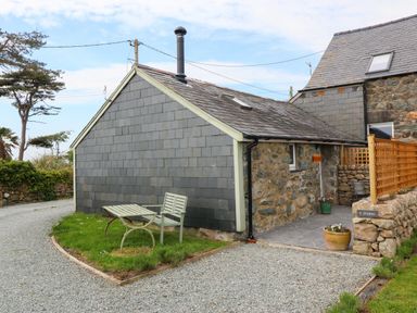A stone and slate cottage with a small patio and outdoor bench at Y Stabl in Dyffryn Ardudwy